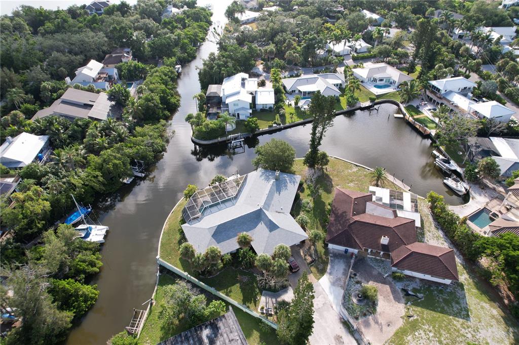 An aerial view shows waterfront homes with private docks along a canal in a residential neighborhood — 6937 MIDNIGHT PASS ROAD, SARASOTA, FL