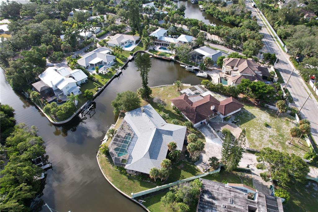 An aerial view shows several waterfront homes with swimming pools along a winding canal — 6937 MIDNIGHT PASS ROAD, SARASOTA, FL