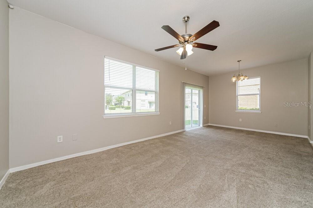 An empty living room features beige carpet, neutral walls, a ceiling fan, and sliding glass doors — 4004 PEMBERLY PINES CIRCLE, ST CLOUD, FL