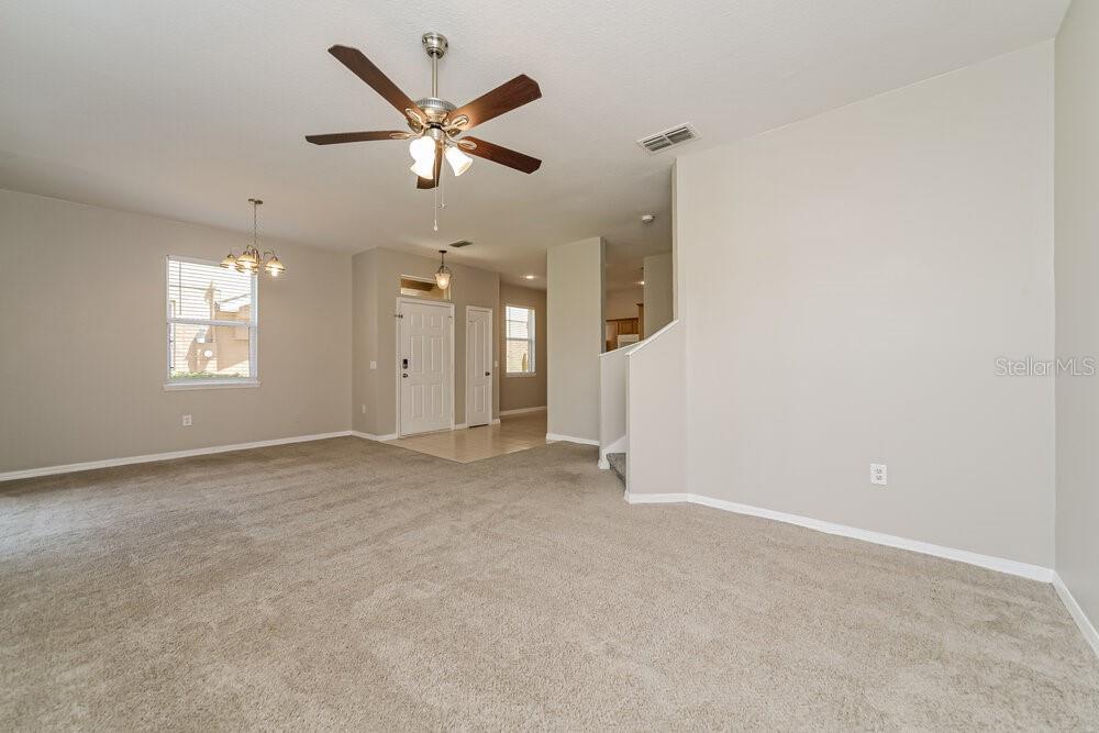An open living room features beige carpeting, a ceiling fan, and a view of the entryway — 4004 PEMBERLY PINES CIRCLE, ST CLOUD, FL