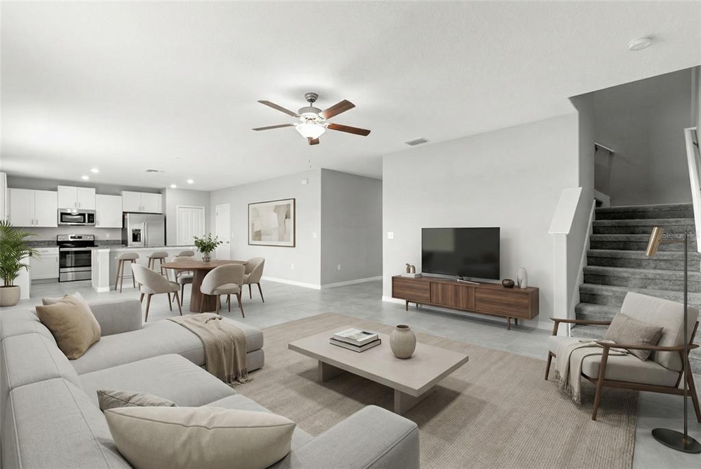 A bright open-concept living room features a sectional sofa, dining area, and kitchen with tile — 5351 NIGHT TIDE LANE, WIMAUMA, FL