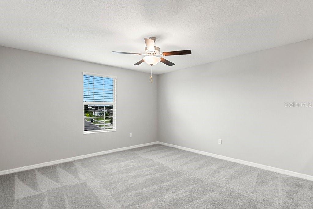 An empty bedroom features light gray walls, gray carpet, and a ceiling fan — 5351 NIGHT TIDE LANE, WIMAUMA, FL