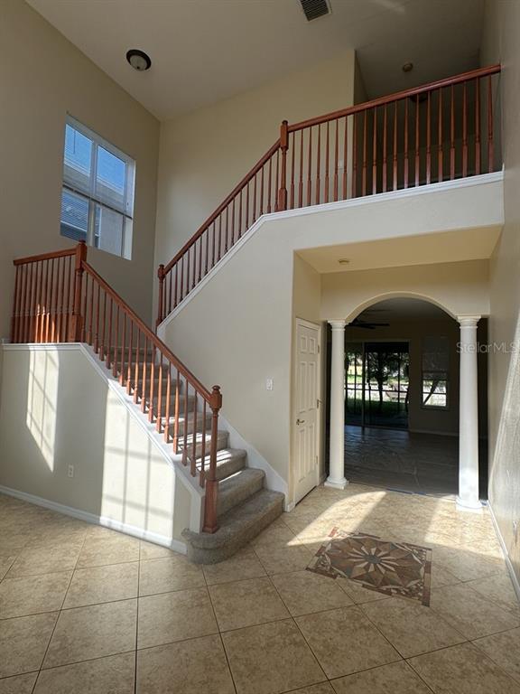 An entryway features a carpeted staircase with wooden railings, tile flooring, and an arched opening — 18048 JAVA ISLE DRIVE, TAMPA, FL
