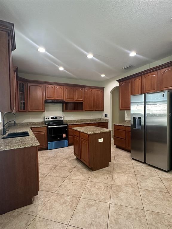 A kitchen features wood cabinets, granite countertops, a center island, and stainless steel appliances — 18048 JAVA ISLE DRIVE, TAMPA, FL