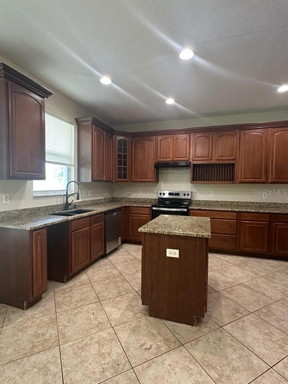 A kitchen features dark wood cabinets, granite countertops, a center island, and tile flooring — 18048 JAVA ISLE DRIVE, TAMPA, FL