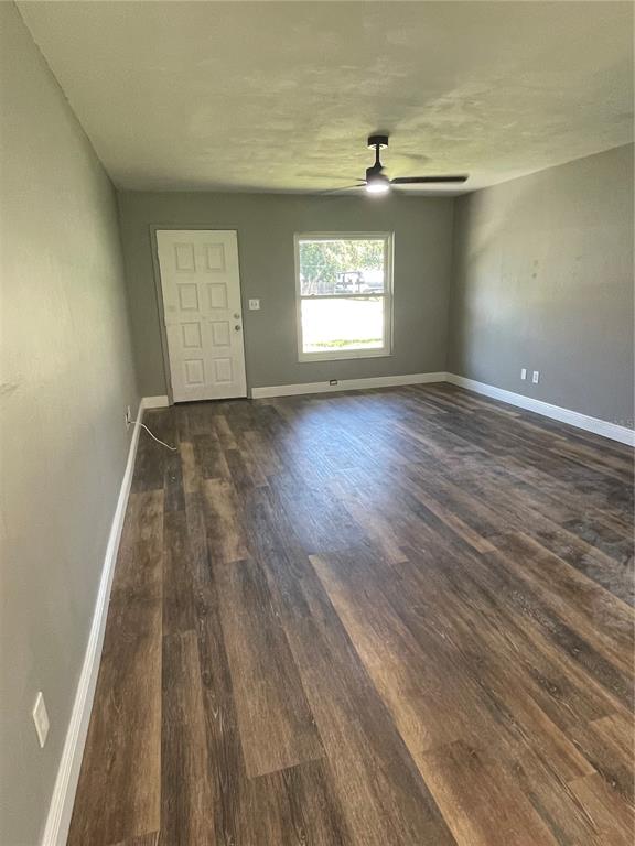 An empty room features gray walls, wood-look flooring, a ceiling fan, and a white door — 11984 SE 95TH TERRACE, BELLEVIEW, FL