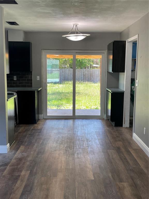 A kitchen and dining area with black cabinets, wood-look flooring, and sliding glass patio doors — 11984 SE 95TH TERRACE, BELLEVIEW, FL