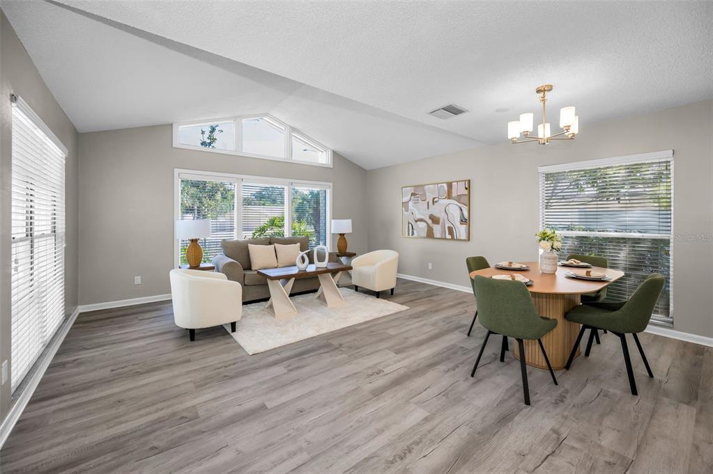 A living and dining area with vaulted ceilings, light wood flooring, and large windows — 7404 CLEARVIEW DRIVE, TAMPA, FL