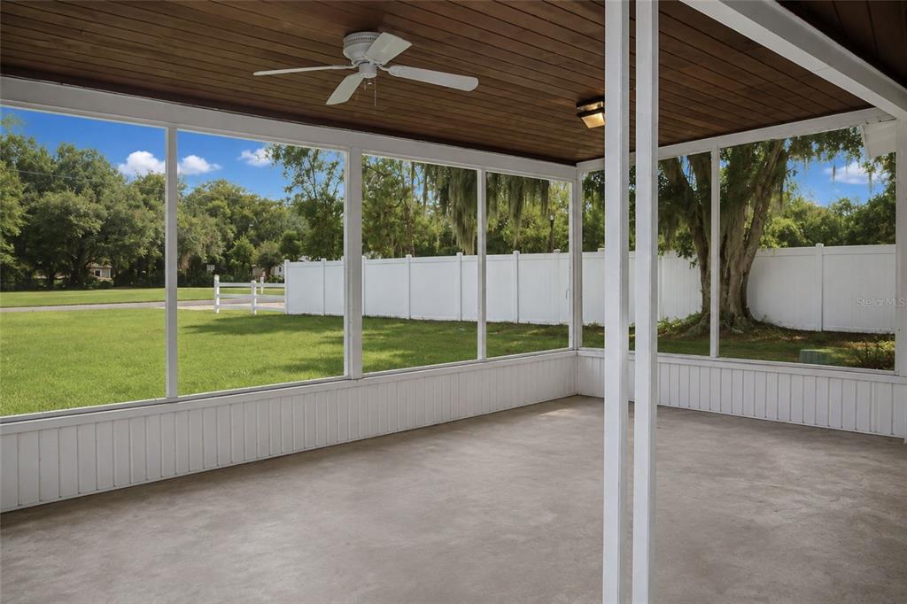 A screened-in porch with a wood-paneled ceiling, ceiling fan, and concrete floor overlooking a yard — 6008 BOB HEAD ROAD, PLANT CITY, FL