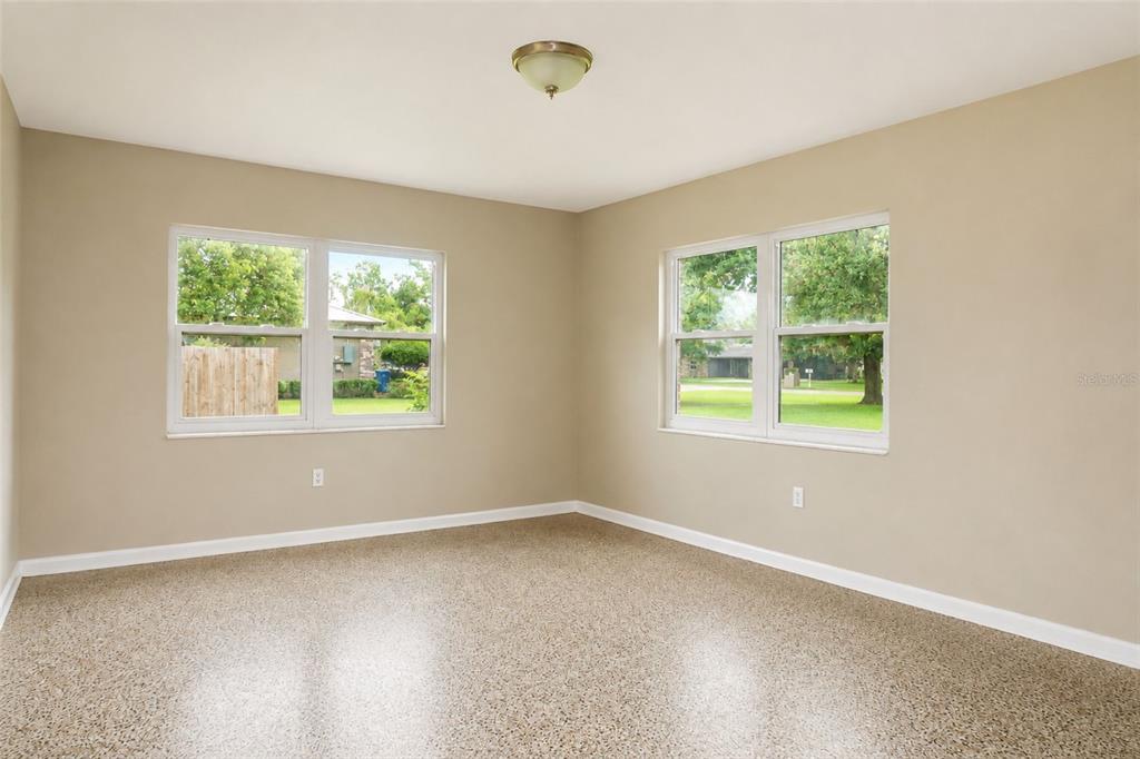 An empty room with beige walls, two windows, and a speckled concrete floor — 6008 BOB HEAD ROAD, PLANT CITY, FL