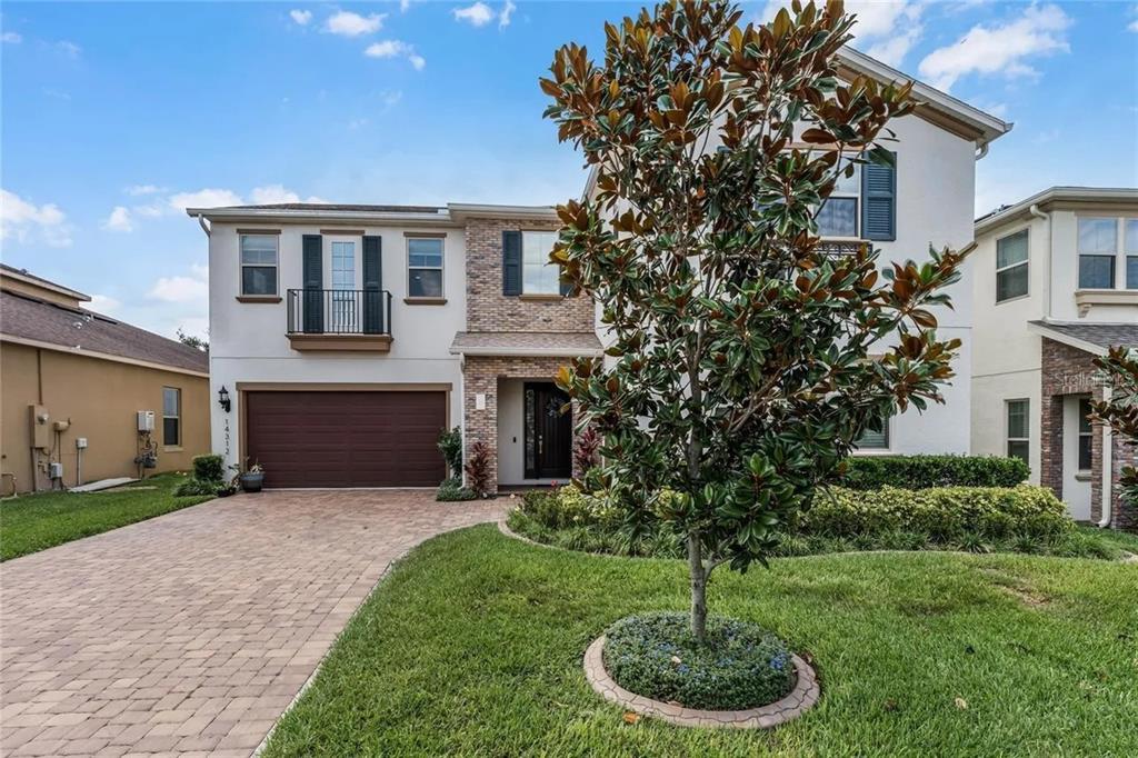 A two-story suburban house with a stone facade, a brown garage, and a front lawn — 14312 SUNBRIDGE CIRCLE, WINTER GARDEN, FL