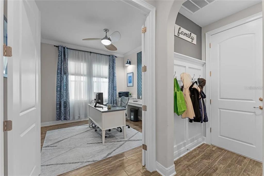 A home office with a desk and rug is visible through an arched doorway near a mudroom — 14312 SUNBRIDGE CIRCLE, WINTER GARDEN, FL