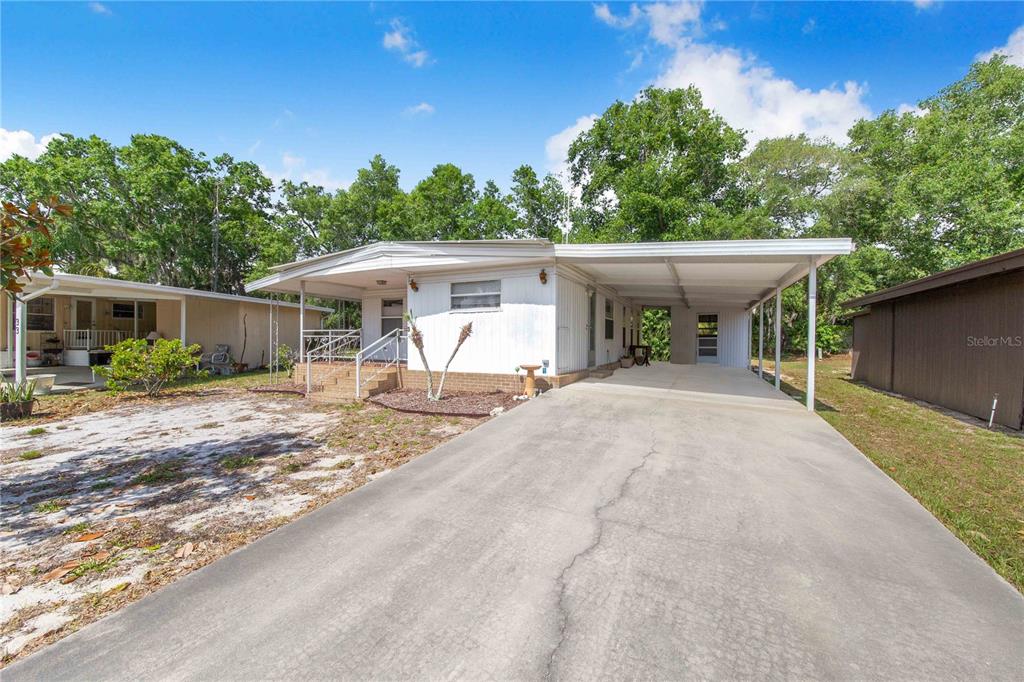 A white mobile home with a concrete driveway and an attached carport — 31 WOODLAND CIRCLE, HAINES CITY, FL