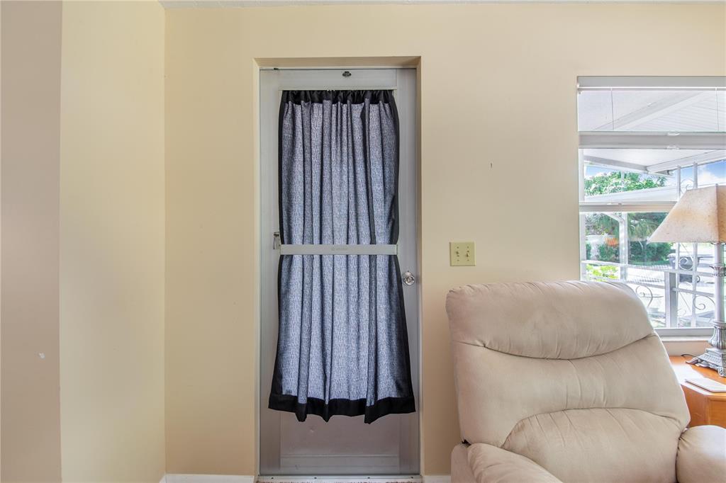 A beige room features a door with a grey curtain and a nearby recliner chair — 31 WOODLAND CIRCLE, HAINES CITY, FL