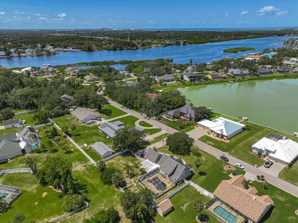 An aerial view shows a suburban neighborhood with houses, swimming pools, and a nearby waterway — 8814 RIVERLACHEN WAY, RIVERVIEW, FL