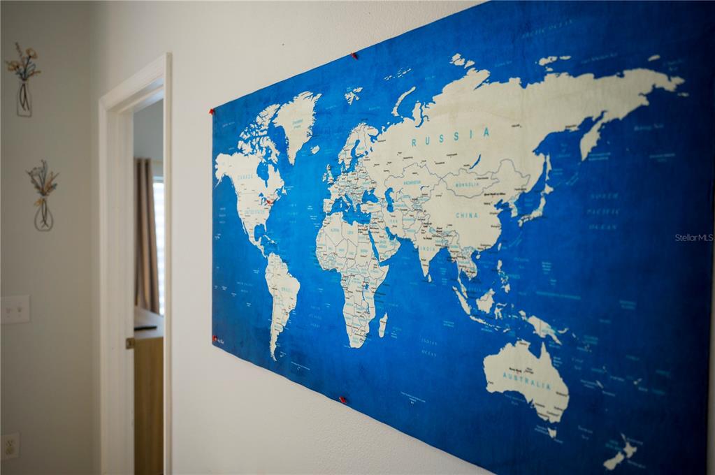 A large world map is mounted on a white wall next to a doorway — 2960 KOKOMO LOOP LOOP, HAINES CITY, FL