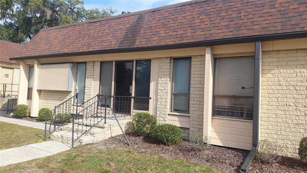 The exterior of a single-story brick office building features a brown shingled roof and stairs — 1103 NW 13TH STREET, GAINESVILLE, FL