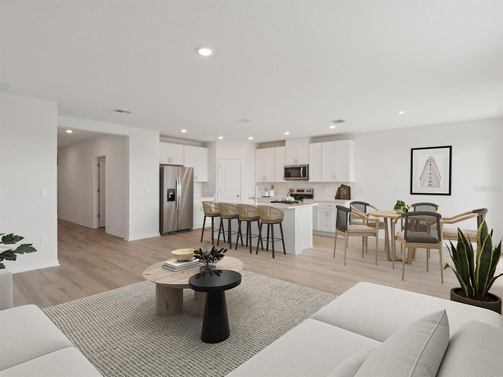 This open-concept kitchen and living area features white cabinetry, a center island, and light flooring — 1789 FOREST RUN LANE, AUBURNDALE, FL