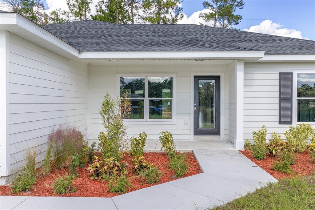 A single-story house with white horizontal siding, a two-car garage, and a dark shingled roof — 15308 SW 56TH TERRACE ROAD, OCALA, FL