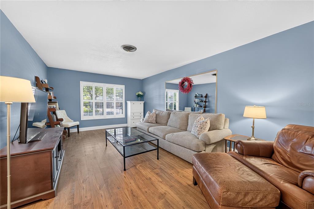 A living room features blue walls, a gray sofa, a leather chair, and wood flooring — 433 GILBERT ROAD, WINTER PARK, FL