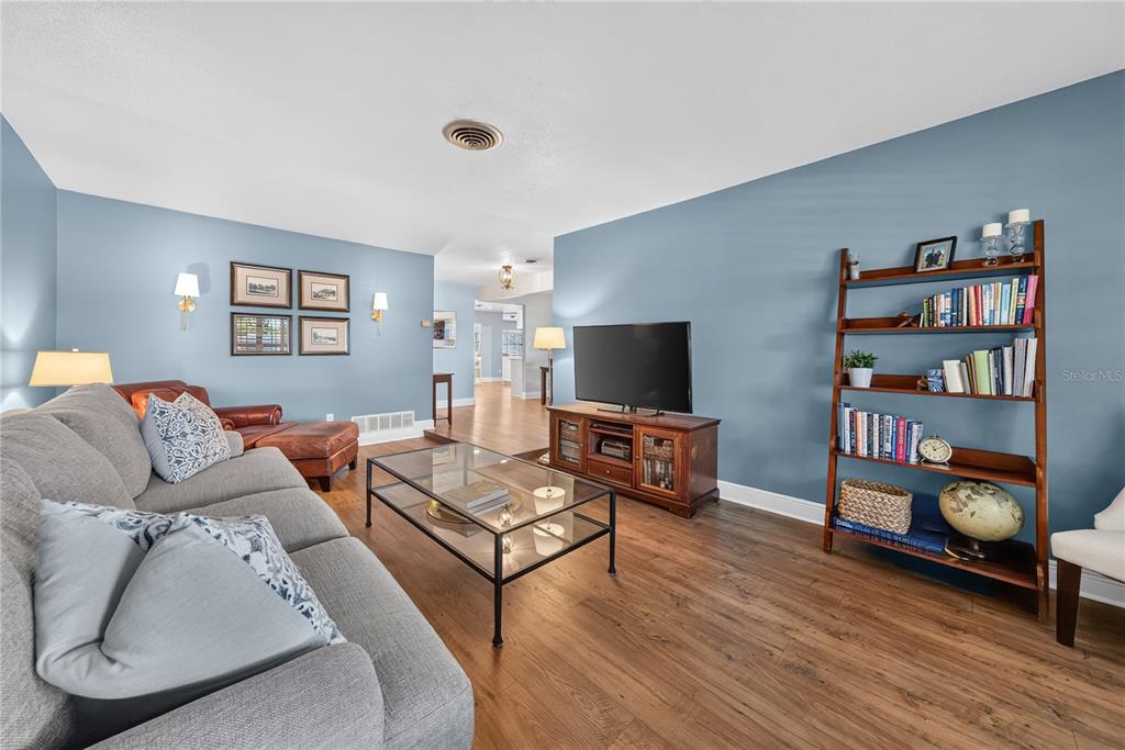 A living room features blue walls, wood flooring, a grey sofa, and a wooden bookshelf — 433 GILBERT ROAD, WINTER PARK, FL