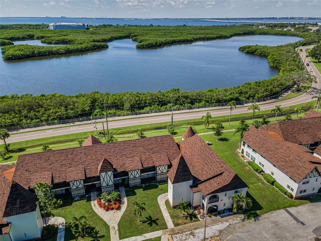 An aerial view shows a multi-story building with a brown roof near a large lake — 320 N BAYSHORE BOULEVARD UNIT 107, CLEARWATER, FL