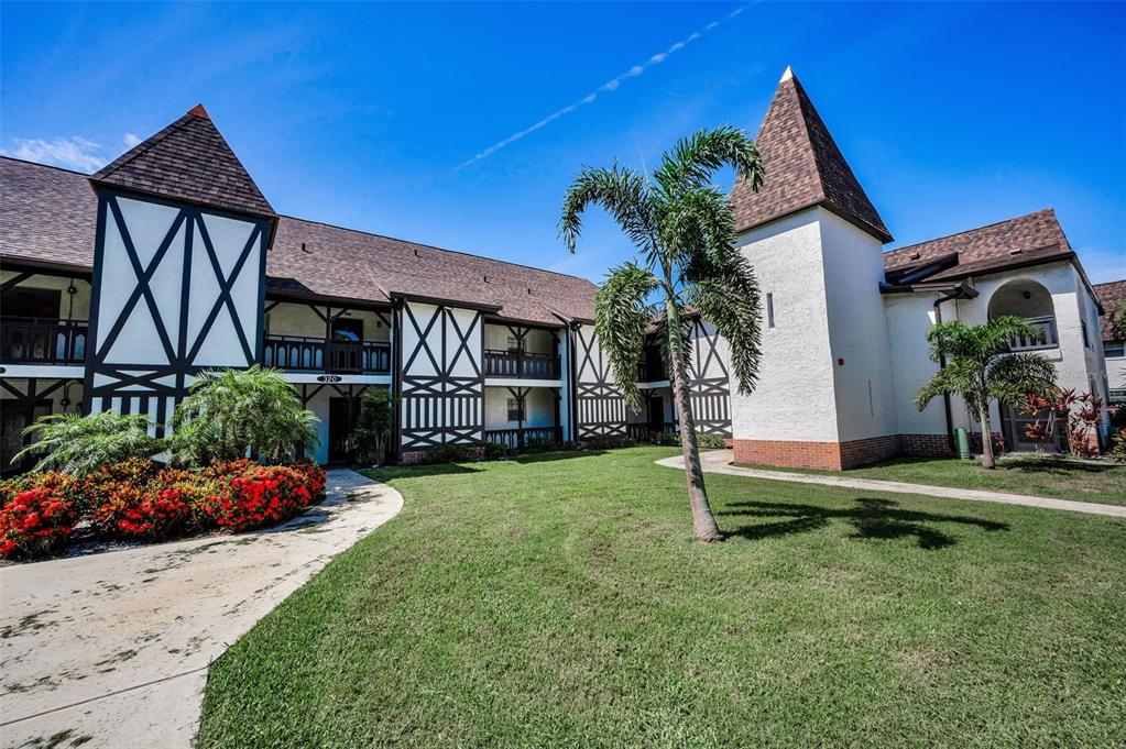 A two-story building with Tudor-style timber framing, a brown shingled roof, and a grassy courtyard — 320 N BAYSHORE BOULEVARD UNIT 107, CLEARWATER, FL