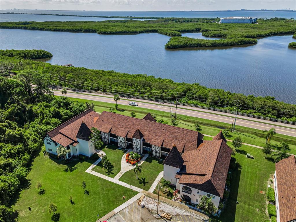 An aerial view shows a multi-story building with a brown roof near a coastal waterway — 320 N BAYSHORE BOULEVARD UNIT 107, CLEARWATER, FL