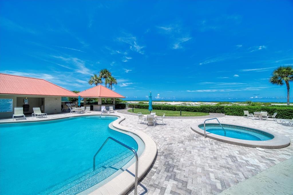 A swimming pool and hot tub sit on a paved patio overlooking the ocean — 1290 GULF BOULEVARD UNIT 1406, CLEARWATER, FL