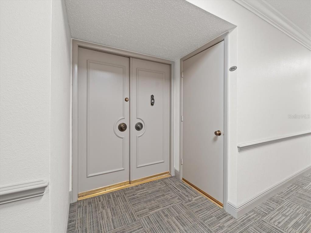 A hallway features a set of double doors and a single door labeled 806 — 1400 GULF BOULEVARD UNIT 806, CLEARWATER, FL