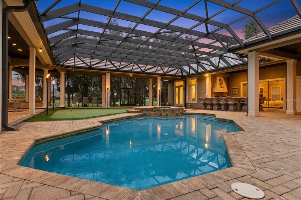 A screened-in patio features a swimming pool, a small putting green, and an outdoor kitchen — 3355 LAKEVIEW OAKS DRIVE, LONGWOOD, FL