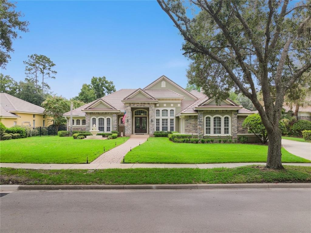A single-story house with a stone facade, tiled roof, and a front lawn with a fountain — 3355 LAKEVIEW OAKS DRIVE, LONGWOOD, FL