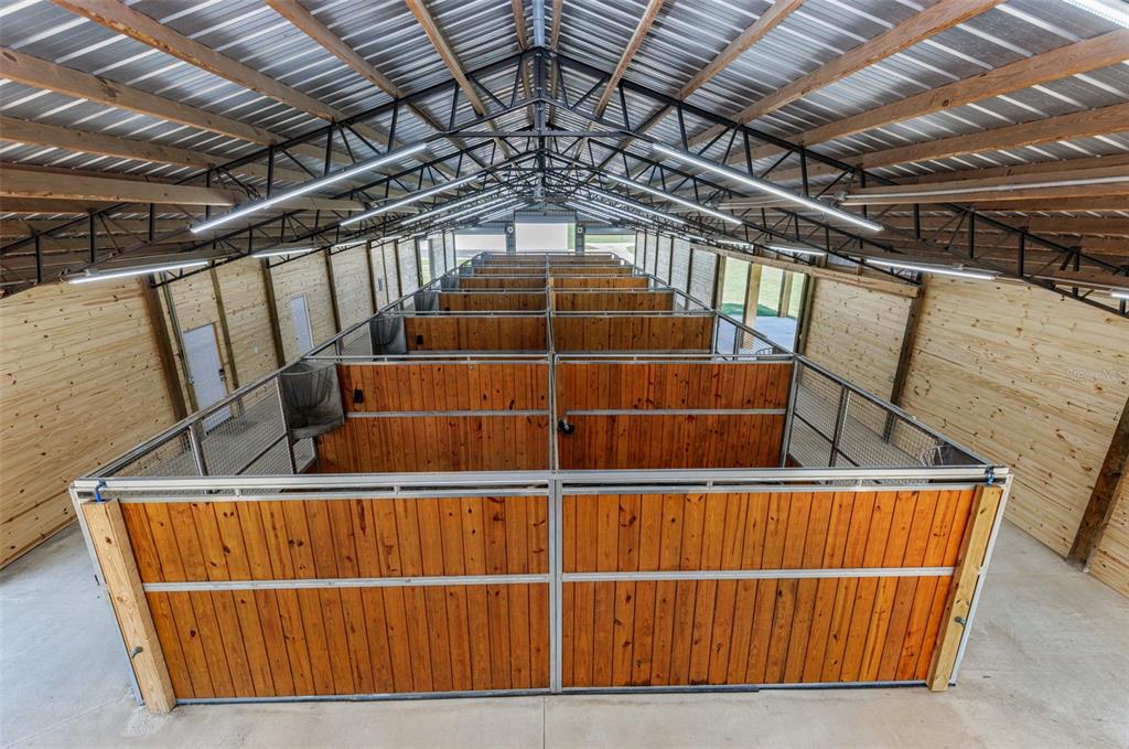 An elevated view of a horse barn interior featuring multiple wooden stalls and metal trusses — 1285 102ND BLVD A UNIT (Option 1), WILDWOOD, FL