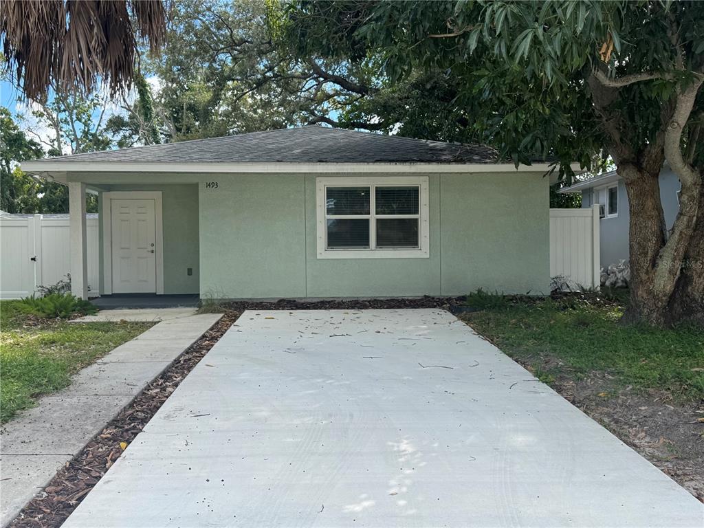 A white vinyl fence stands in a grassy backyard with trees and a detached panel — 1493 CLEVELAND STREET, CLEARWATER, FL