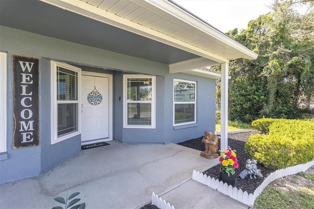 A blue house exterior features a covered porch, a white front door, and landscaping — 10513 BLYTHVILLE ROAD, SPRING HILL, FL