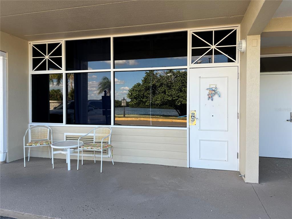 A white door and large windows overlook a waterfront area with two chairs outside — 611 DESTINY DRIVE UNIT 501, RUSKIN, FL