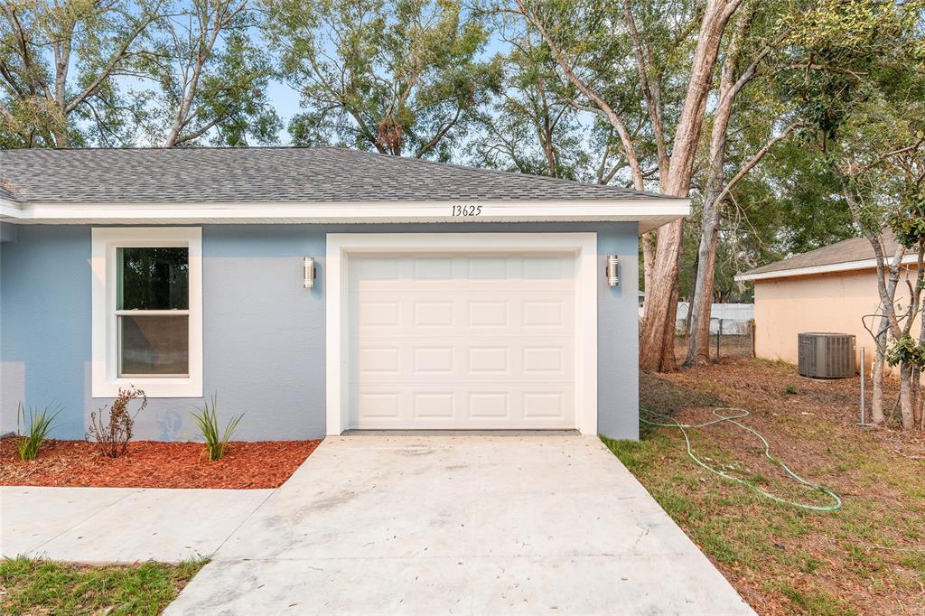 A light blue house exterior features a single-car garage and a concrete driveway — 2688 SW 150TH COURT, OCALA, FL