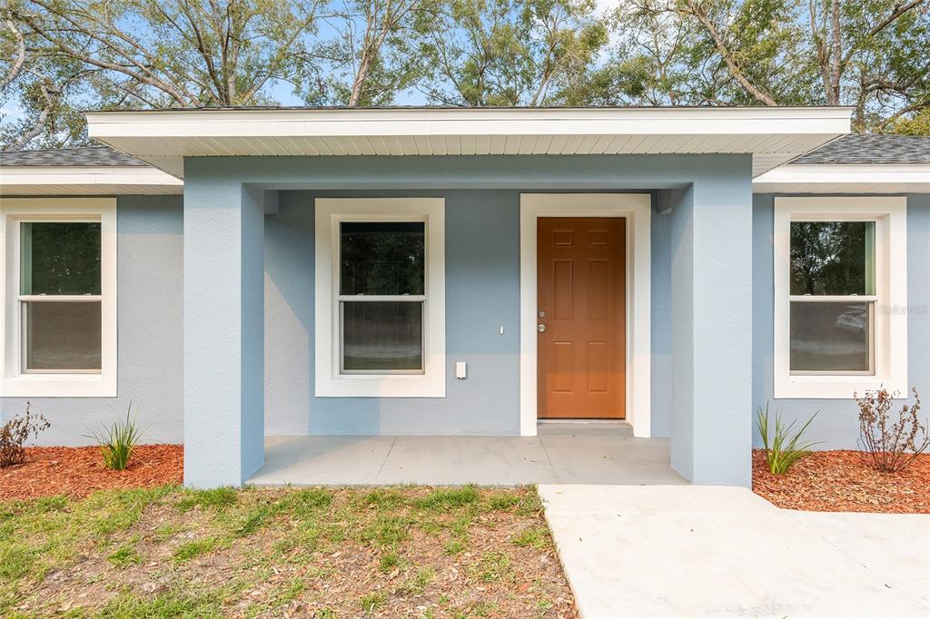 A light blue house exterior features a covered front porch, white trim, and a walkway — 2688 SW 150TH COURT, OCALA, FL