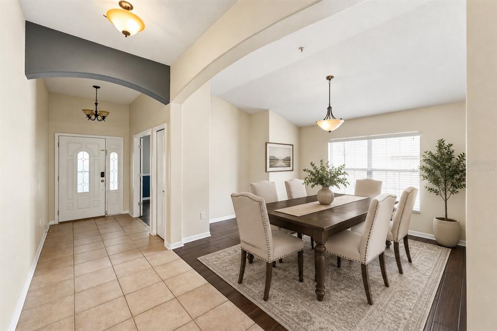 A dining room with a wooden table and chairs sits adjacent to a tiled entryway — 13368 MANDALAY PLACE, SPRING HILL, FL