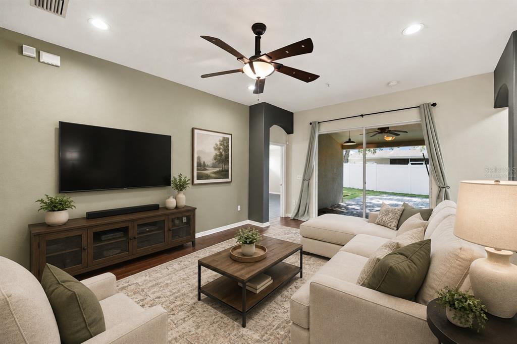 A living room with a sectional sofa, television, coffee table, and sliding doors to a patio — 13368 MANDALAY PLACE, SPRING HILL, FL