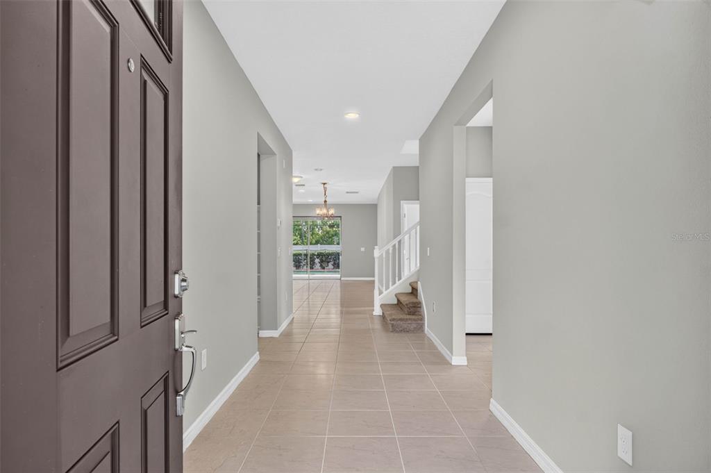 A view from an open front door into a tiled foyer with a staircase — 8924 BENGAL COURT, KISSIMMEE, FL