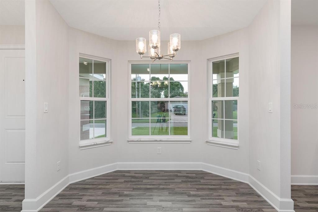 A dining nook with a chandelier, three windows, and wood-look flooring — 23 RAMROCK LANE, PALM COAST, FL