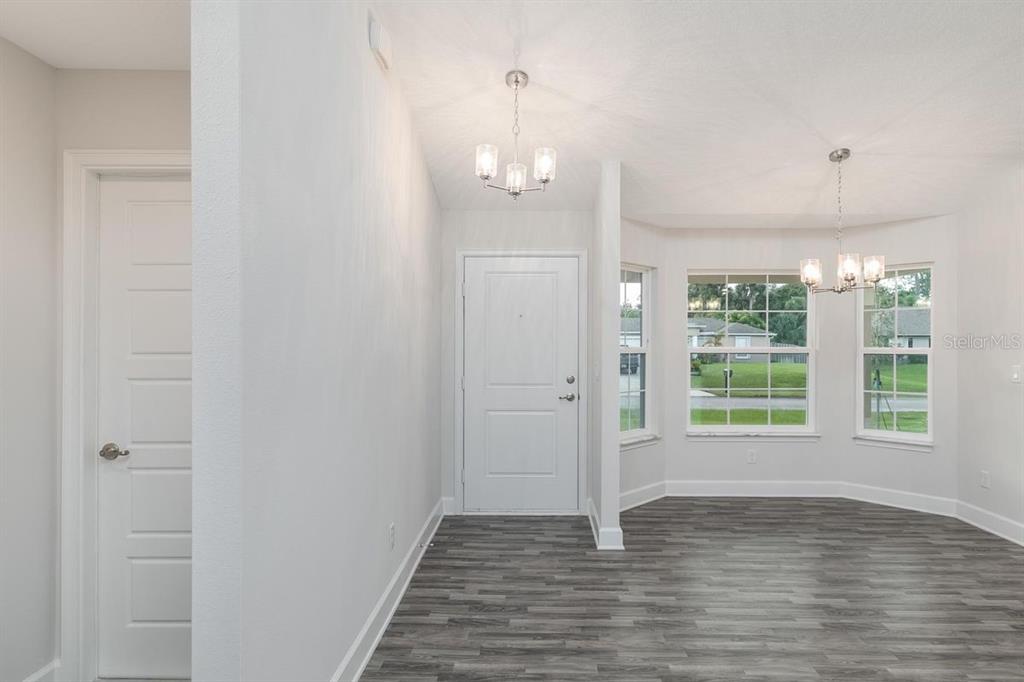 An entryway with a white door and a dining area featuring gray wood-look flooring — 23 RAMROCK LANE, PALM COAST, FL