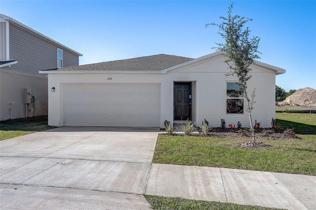 A single-story house with a white stucco exterior, a two-car garage, and a dark front door — 1317 GIDEON STREET SW, PALM BAY, FL