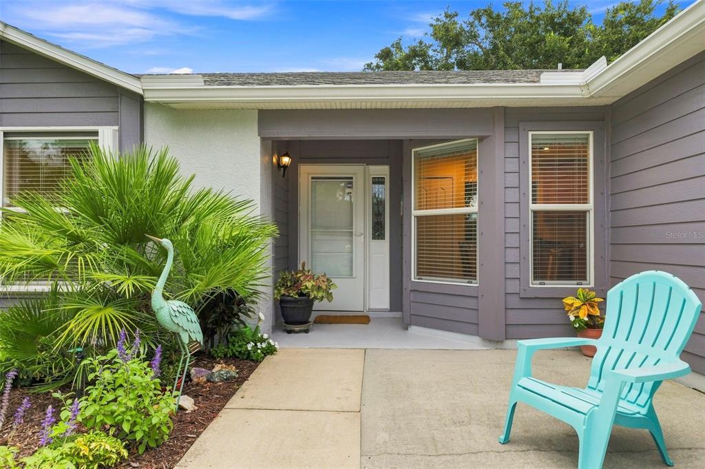 A front porch with a light blue chair, a potted plant, and a front door — 1531 DALLAM AVENUE NW, PALM BAY, FL