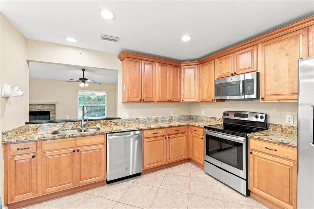 A kitchen with light wood cabinets, granite countertops, and stainless steel appliances — 1531 DALLAM AVENUE NW, PALM BAY, FL