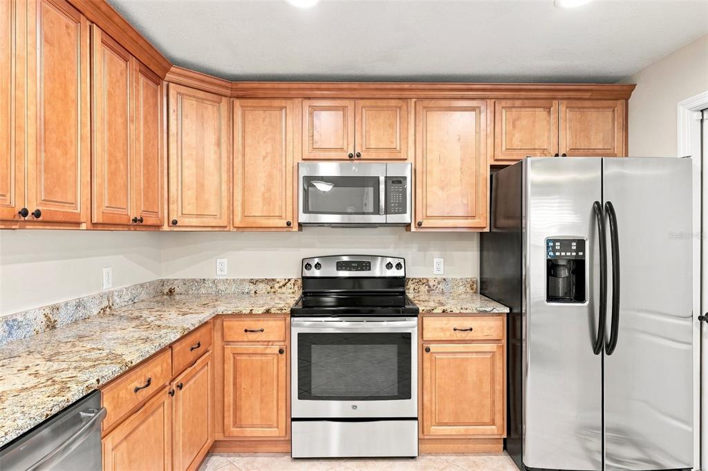 A kitchen features light wood cabinets, granite countertops, and stainless steel appliances — 1531 DALLAM AVENUE NW, PALM BAY, FL