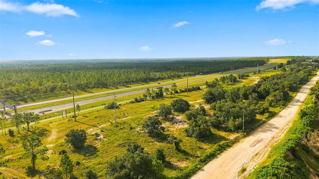 An aerial view shows a dirt road running alongside a highway through a grassy landscape — 5050 W HOSKINS LANE, LECANTO, FL