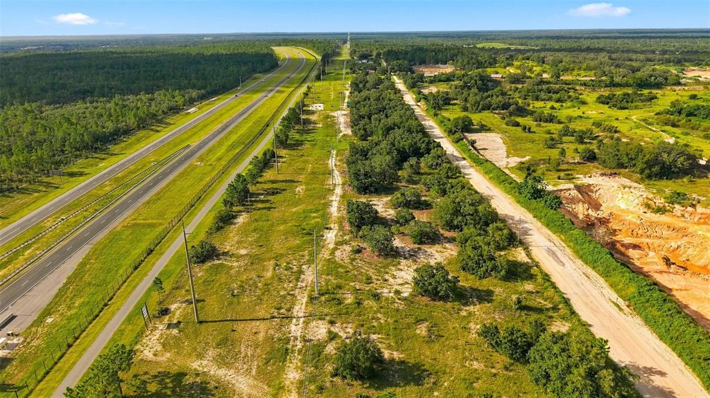 An aerial view shows a highway running parallel to a dirt road and undeveloped land — 5050 W HOSKINS LANE, LECANTO, FL