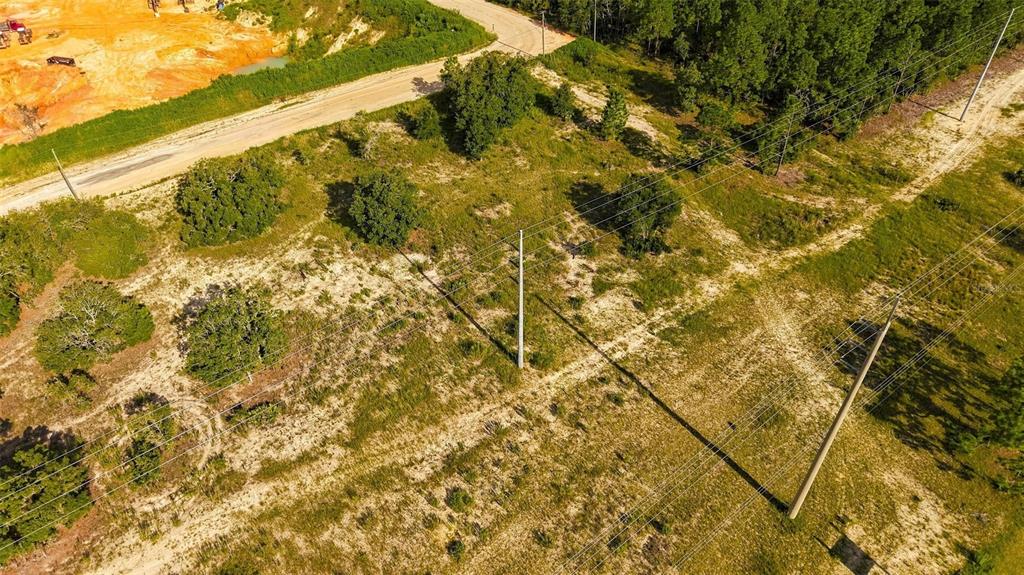 An aerial view shows a grassy, undeveloped lot with utility poles and power lines — 5050 W HOSKINS LANE, LECANTO, FL